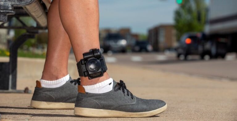 man wearing ankle monitoring device while sitting on a bench