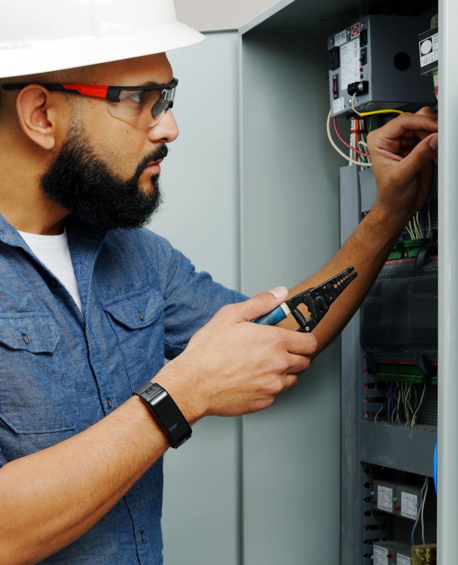 Electrician worker wearing BI SmartBAND 1.0 wrist-worn device works on electric box, showcasing workplace wearable technology.