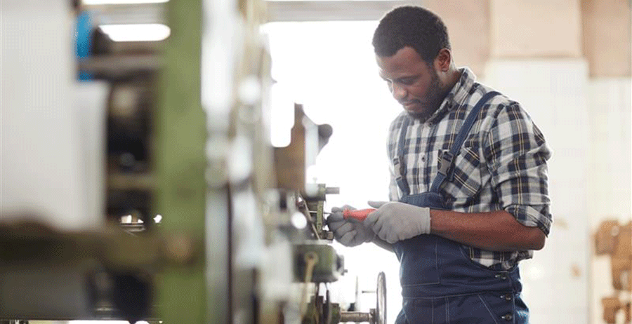 A man on home confinement works at a lathe in his job, showing how electronic monitoring enables people to work while serving their sentence.