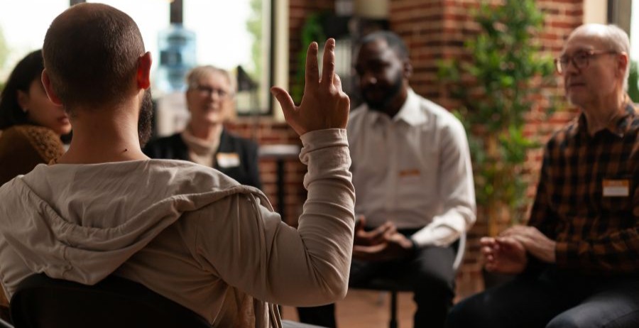 Man speaking during a National Recovery Month recovery support meeting with a therapist and group participants.